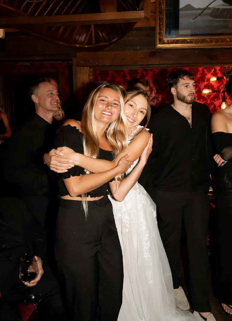 Lucy Spotts hugging the bride at an indoor reception.